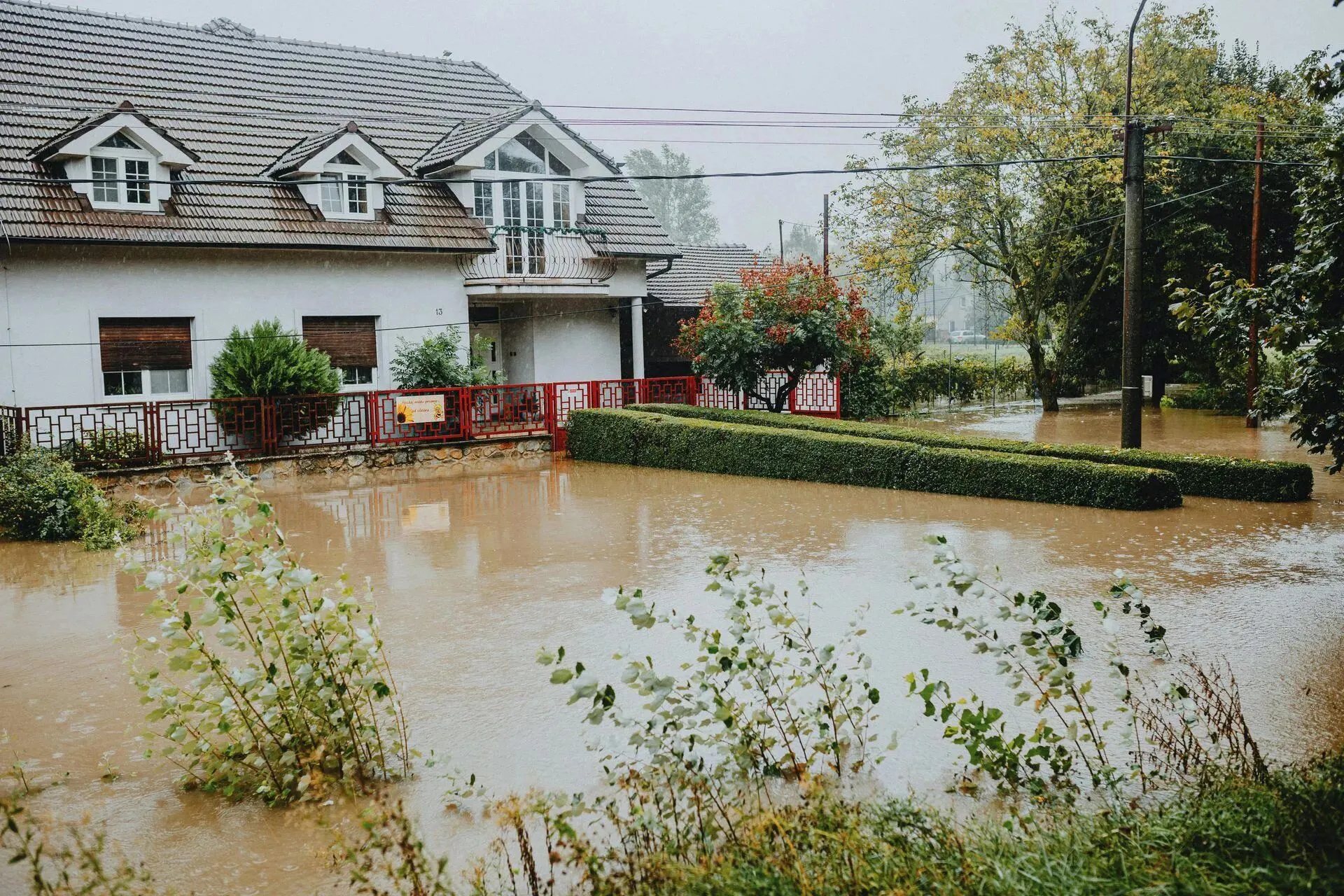 Flooded residential property with water surrounding the house and garden, illustrating significant water damage risks after winter freeze.